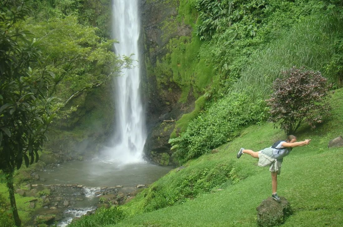 Qigong beside a waterfall in green hills